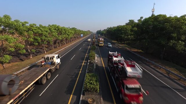 GRESIK, INDONESIA - JULY 18, 2026: Industrial logistics transportation on a highway in Prambangan area with a flatbed truck carrying steel coils and a towing truck, top view.