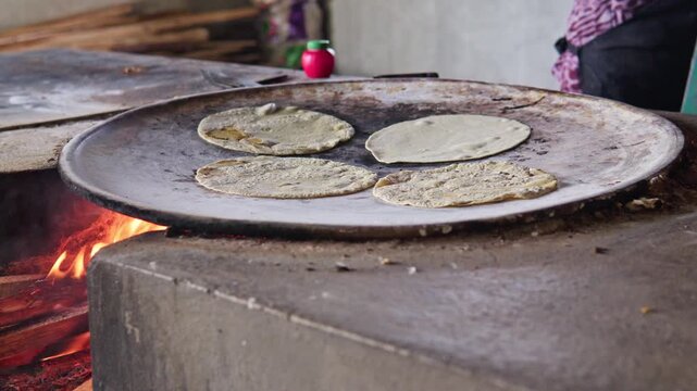 Mexican cook preparing traditional corn tortillas on a comal