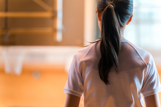 The back view of a female student in gym clothes in the school gymnasium.