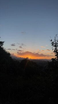 Golden sunset over mountain landscape with silhouette trees and orange sky