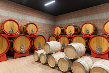 Obraz premium Oak Wine Barrels Aging in a Cellar. Traditional Winemaking Process and Wine Culture Interior, Italy