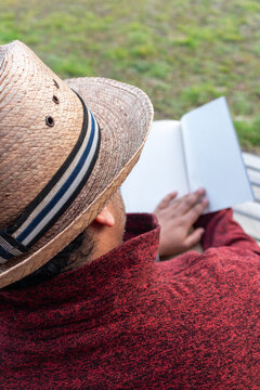 Anonymous reader enjoying a book on a terrace with grass background