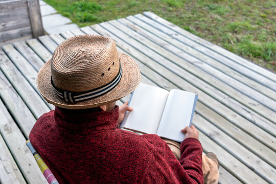 Latino anonymous reader in a straw hat holding an open book template, horizontal view