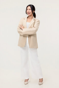 Confident young Asian businesswoman standing with arms crossed and smiling, corporate studio portrait on white background.