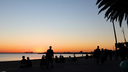 Obraz premium Silhouetted People Gathering on Brighton Beach During a Golden Sunset
