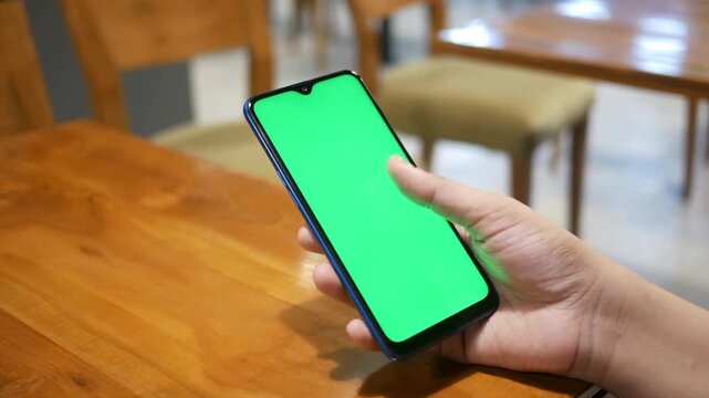 Person holding smartphone with green screen mockup, 4k video