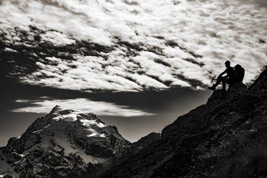 Mountaineer in backlight with cloudy sky in front of Ortler summit massif, Trafoier Tal, Meran, Vinschgau, South Tyrol, Italy