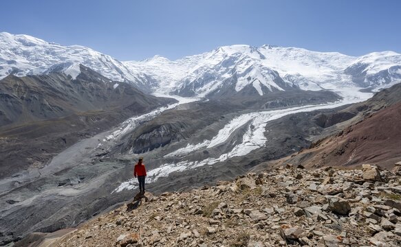 Mountaineer at Traveller's Pass with view of impressive mountain landscape, high mountain landscape with glacier moraines and glacier tongues, glaciated and snow-covered mountain peaks, Lenin Peak and Peak of the XIX Party Congress of the CPSU, Trans Alay Mountains, Pamir Mountains, Osh Province, Kyrgyzstan