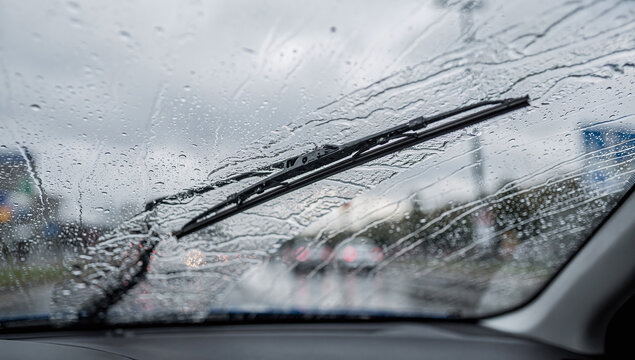 A car windshield covered in raindrops during a rainy day
