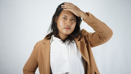 Fototapeta premium Young Woman in Brown Blazer and White Shirt Touching Forehead, Studio Shot