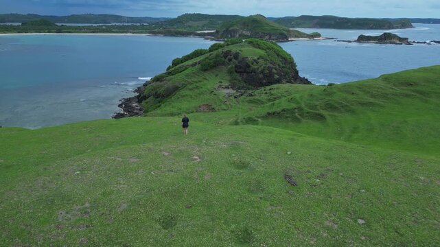Woman Resting On Hilltop Overlooking Turquoise Bay And Narrow Headland Seated Figure Gazes At Calm Water, Soft Light,Aerial Composition Evokes Peace And Contemplation, Bukit Merese,Lombok, Tanjung Ann