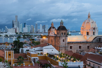 Fototapeta premium Blue hour view of Cartagena's historic walled city with the Cathedral of Saint Catherine of Alexandria and the modern Bocagrande skyline in the background, Cartagena, Colombia
