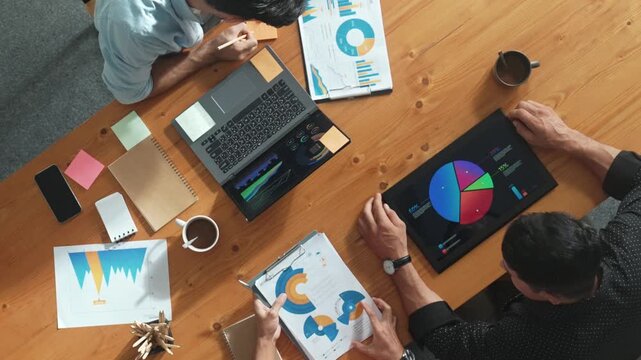 Top aerial view of caucasian business people sharing idea and writing report. Professional diverse people working together and brainstorming marketing plan at meeting table with graph. Convocation.