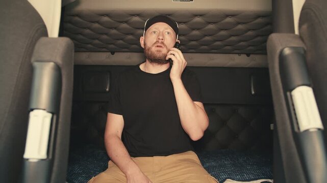 Truck driver talking on the phone inside sleeper cabin