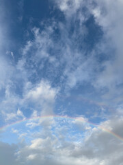 Obraz premium Beautiful rainbow in the blue sky with white clouds
