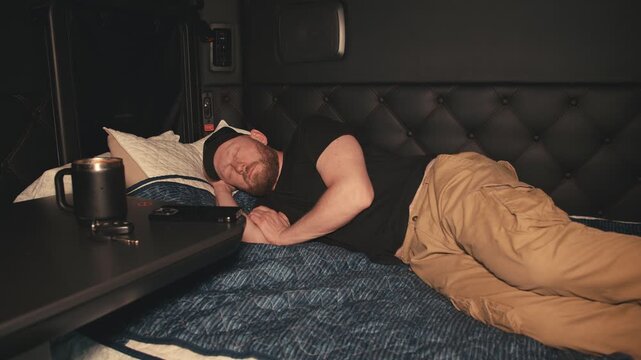 Truck driver waking up from phone notification in sleeper cabin