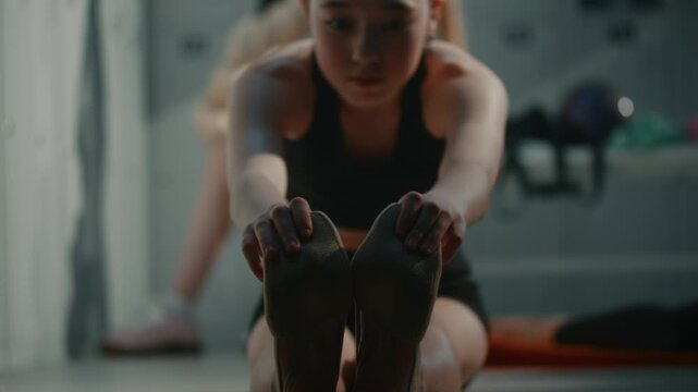 In Bright Studio Changing Facility, Young Female Dancer Works on Flexibility by Performing Strict Toe Touch Stretch on Floor. Athletic Routine and Physical Conditioning of Generation Z Gymnasts.