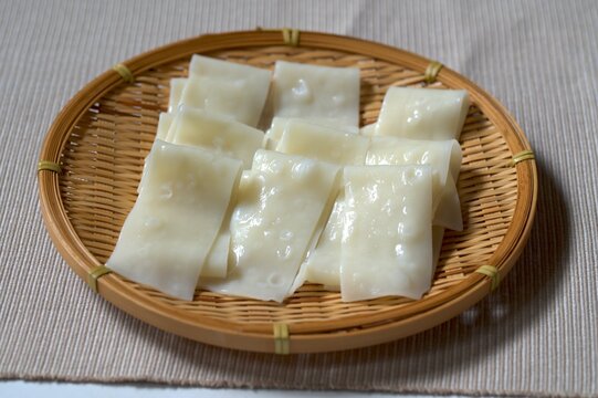 ざるに乗ったツヤのある幅広うどんと箸のクローズアップ