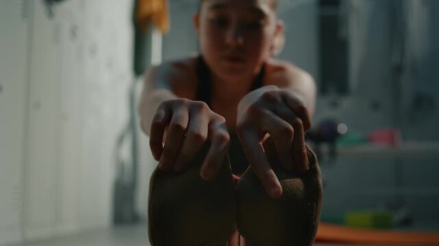 Close Up Hands Young Female Rhythmic Gymnast Grabbing Toes. Wearing Traditional Rhythmic Gymnastics Half Shoes, Girl Performs Deep Seated Forward Bend on Locker Room Floor. Gymnastics School Routine.