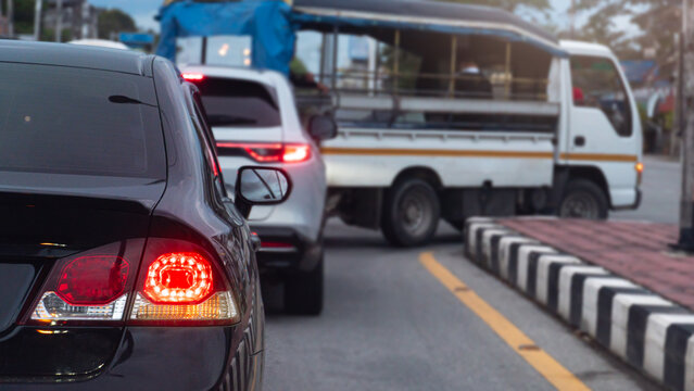 Busy traffic scene showing a line of vehicles. Including a car and a small truck waiting on a city road. Focus is on the rear tail lights during a daily commute. Outstanding of turn on right signal.
