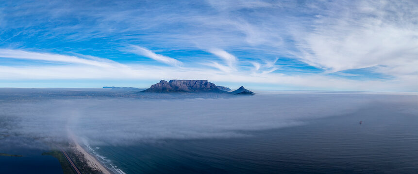 Table Mountain rising up above winter mist over Table Bay. Cape Town city and foreground obscured. Aerial stitched pano.