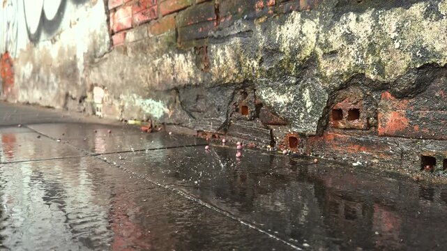 Old ruined brick Wall and Wet Glistening Pavement. Rainy Urban Atmosphere Close up