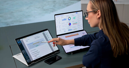 Obraz na płótnie Canvas Woman Uses Dual Touchscreen Laptop To Monitor Compliance