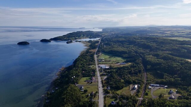 Aerial view of Bic National Park coastline, forest, campground and calm bay under blue sky. g.