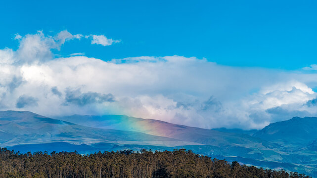 Andean rainbow over mountains and dramatic clouds in Quito, Ecuador