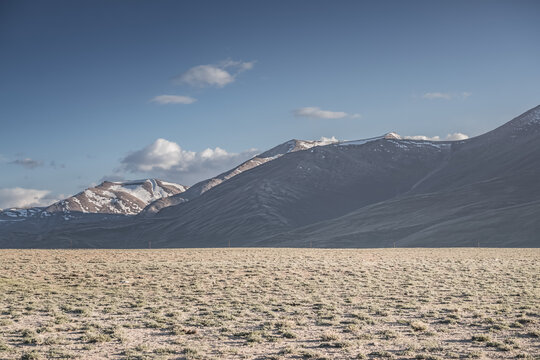 A desert landscape in the highlands of the Pamirs on a sunny summer day with mountains, peaks, and ridges of the Tien Shan mountain range