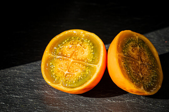 Bright and vibrant slices of fresh sapote on a dark background