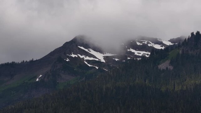 Aerial of Cascade Mountains in Gifford Pinchot National Forest near Packwood Washington with snow patches and foggy conditions obscuring the peaks in summer