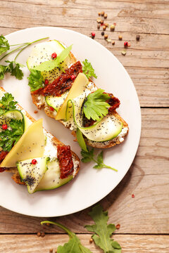 Gourmet bruschetta toast with zucchini and sun dried tomatoes on wooden table