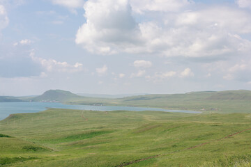 Fototapeta premium Vast scenic panoramic view of green hills and large lake water under cloudy sky