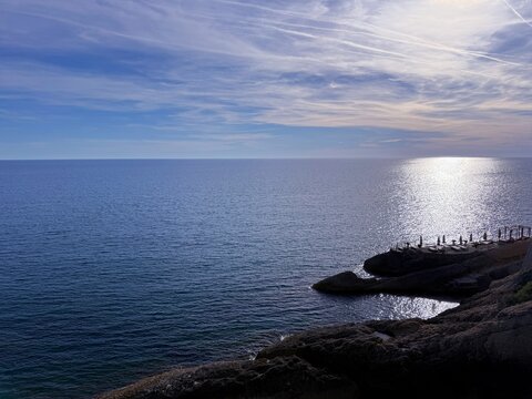 Calm sea, dusk sky and beach on the rocks in summer evening, sense of relax and serenity.