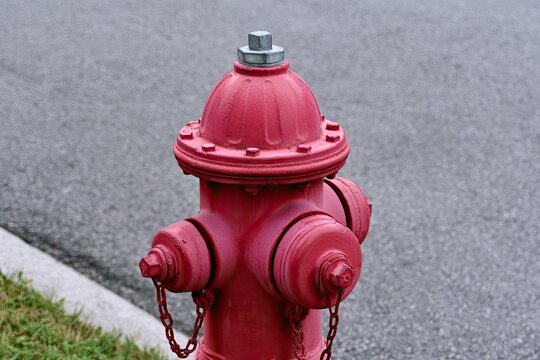 Red fire hydrant stands on paved ground next to a curb