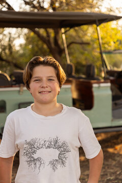 portrait of young man posing next to vintage safari vehicle, Zambezi National Park, Zimbabwe, Africa