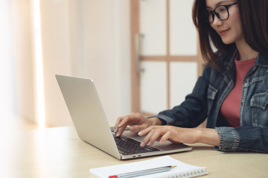 Asian woman working remotely, using laptop, surfing the net at cafe modern workspace. online job, freelance at work, business casual concept.