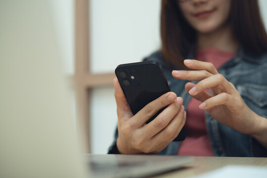 Business woman using smartphone during working on laptop at home office, surfing the net, social media network, modern lifestyle