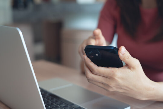 Woman using smartphone with laptop on table during remote working at modern workspace, social media, online business lifestyle