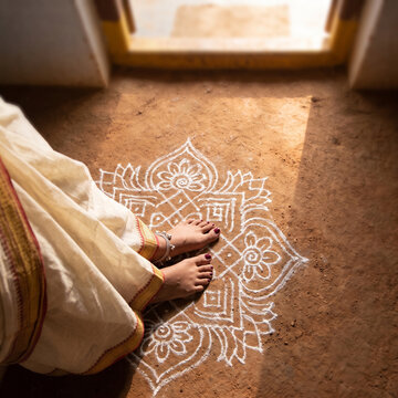 Woman feet on traditional rangoli floor art. Indian cultural home decoration design.