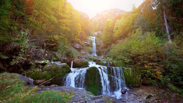 Backlit waterfall glowing in golden sunlight through rising mist