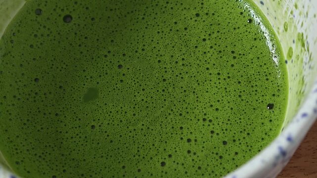 Matcha in bowl with bamboo whisk.
