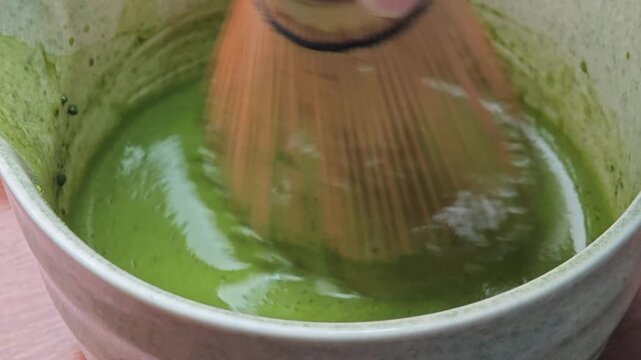 Matcha in bowl with bamboo whisk.