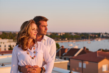 Obraz premium Mature Couple Embracing on Rooftop Balcony With Sea View at Sunset in Umag, Croatia