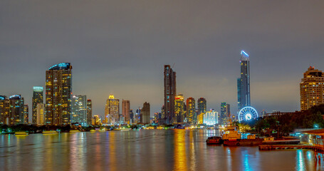 Obraz premium Panoramic Bangkok skyline at night along Chao Phraya River, Thailand, illuminated skyscrapers, modern architecture and urban waterfront cityscape. Financial district and waterfront architecture.