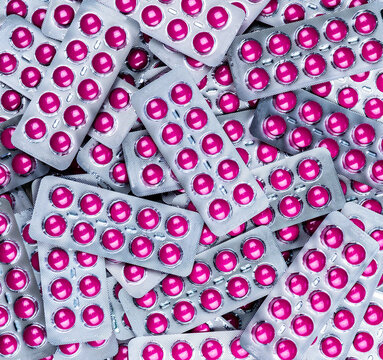 Pink medicine tablets in blister packs arranged as a pharmaceutical background. Prescription medication, healthcare supplies, pharmacy inventory, medical treatment and drug packaging texture.