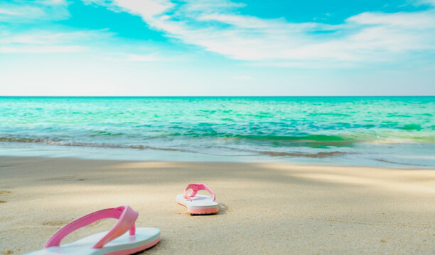 Pink and white sandals on sand beach. Casual style flip-flop were removed at seaside. Summer vacation on tropical beach. Fun holiday travel on sandy beach. Summertime. Summer vibes. Relaxing time.