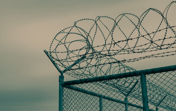Prison security fence. Barbed wire security fence. Razor wire jail fence. Barrier border. Boundary security wall. Prison for arrest criminals or terrorists. Private area. Military zone concept.