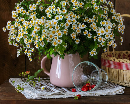 bouquet of garden daisies and strawberries on a dark background. summer still life with flowers in a jug and berries.
